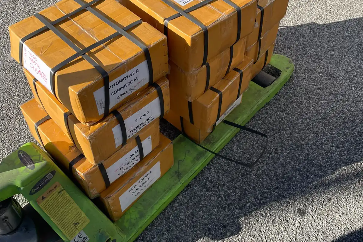 Strapped cartons of automotive parts on a pallet jack, collected by Red Nav for delivery in Perth